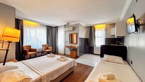 Habitación de hotel con dos camas, un escritorio, una silla, un televisor y una ventana con cortinas.