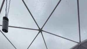 Een tentkamer met een bed, een kleine tafel met een lantaarn en een metalen bedframe.