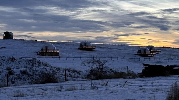 A snowy landscape with several dome-shaped structures, possibly accommodations, on a hill. - Cozy Geodesic Glamping Dome on a Canadian Ranch with Horses, Perfect for a Weekend of Wellness (Redcliff)