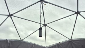 A tent with a bed, two side tables, and a hanging light fixture. - Cozy Geodesic Glamping Dome on a Canadian Ranch with Horses, Perfect for a Weekend of Wellness (Redcliff)