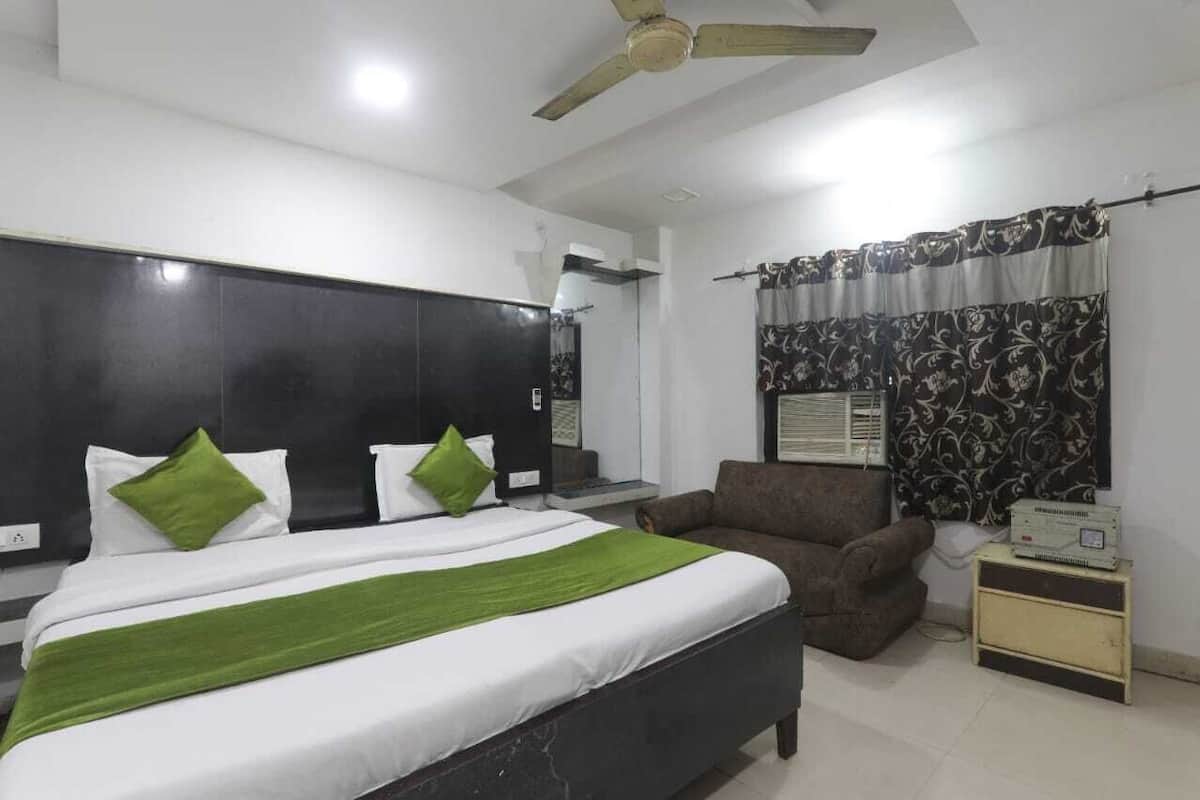 A bedroom with a bed, a chair, a nightstand, a ceiling fan, and a window with curtains.