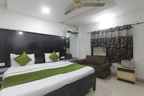 Ein Schlafzimmer mit Bett, Stuhl, Nachttisch, Deckenventilator und einem Fenster mit Vorhängen.
