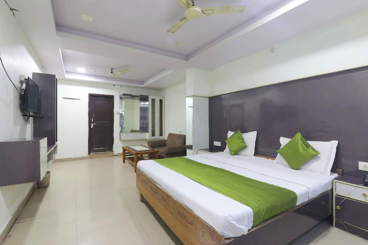 A hotel room with a bed, a desk, a chair, a television, and a ceiling fan.