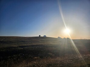 Tasainen maisema, kirkas taivas ja matalalla horisontissa paistava aurinko, joka luo pitkiä varjoja.