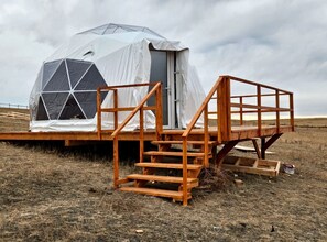 A geodesic dome tent with a wooden staircase leading to a platform. - Simple and Elegant Geodesic Glamping Dome for a Relaxing Weekend to Disconnect Outside of Redcliff, Alberta, Canada (Redcliff)