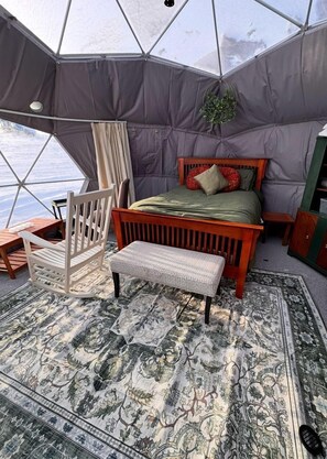 A tented room with a bed, a wooden chair, a bench, and a patterned rug. - Simple and Elegant Geodesic Glamping Dome for a Relaxing Weekend to Disconnect Outside of Redcliff, Alberta, Canada (Redcliff)