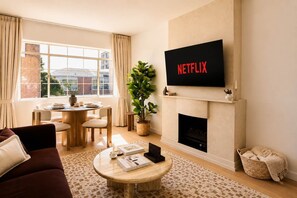 Una sala de estar con chimenea, una mesa de comedor y un televisor sobre la chimenea.