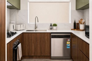 Una cocina moderna con lavavajillas de acero inoxidable, horno empotrado y cocina a gas.