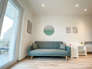 A modern living room with a teal sofa, a round mirror, and minimalist decor. - Panoramic house in the heart of Salento, 20 min from the two seas (Galatina)