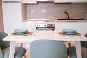 A dining table set with two bowls and two wine glasses, with a modern kitchen in the background. - Panoramic house in the heart of Salento, 20 min from the two seas (Galatina)
