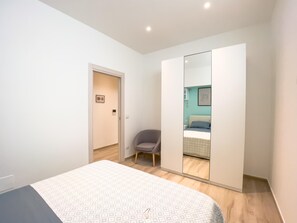 A bedroom with a bed, a chair, a wardrobe, and a door leading to another room. - Panoramic house in the heart of Salento, 20 min from the two seas (Galatina)
