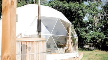 A geodesic dome structure with a wooden deck and a chimney.