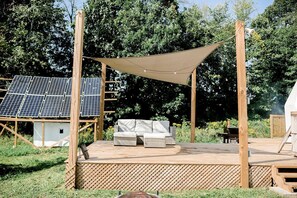 Une terrasse en bois avec un canapé, des panneaux solaires et un auvent.