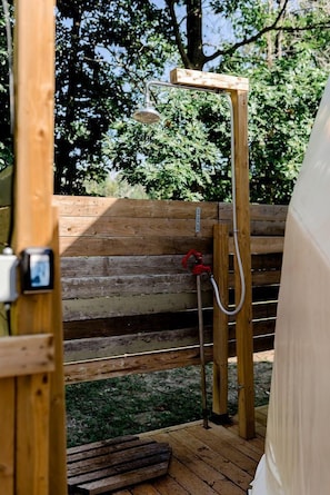 A wooden deck with a shower area, a bench, and a wooden fence.