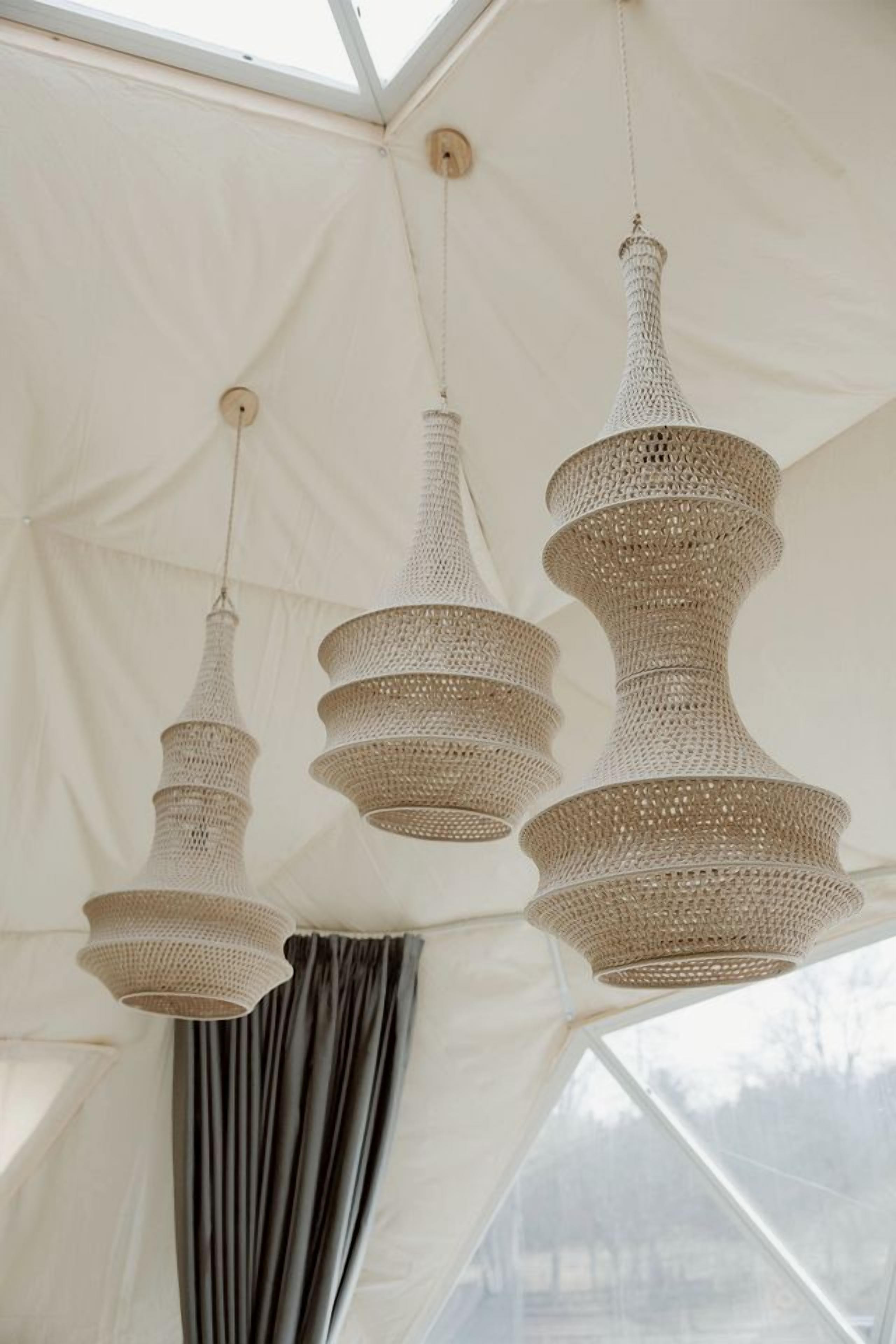 A tent-like structure with a high ceiling and three hanging woven light fixtures.