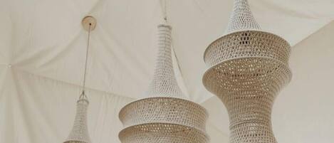 A tent-like structure with a high ceiling and three hanging woven light fixtures.