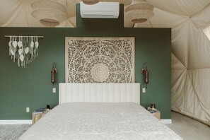 Una habitación con carpa que incluye una cama, decoración en la pared y un ventilador de techo.