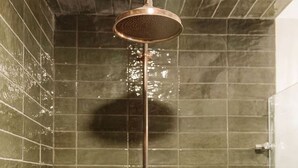 A shower with a copper fixture, a tiled wall, and a visible shadow. - Peaceful Boho Dome Escape with Open Field Views in Ontario, Canada (Marmora)