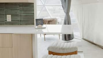 Une pièce aménagée comme une tente, avec un banc en bois, une table blanche et une suspension lumineuse.