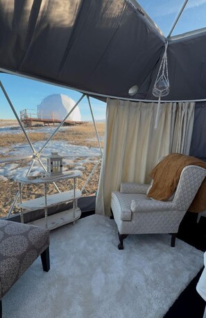 A tent with a view of a snowy landscape, a cushioned chair, a small table with a lantern, and a white carpet. - Tranquil Dome on the Calm Prairies of Alberta, Canada, near Medicine Hat and Redcliff (Redcliff)