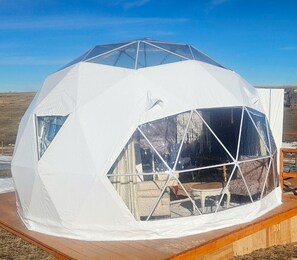 A geodesic dome structure with a transparent window section, wooden deck, and a clear sky. - Tranquil Dome on the Calm Prairies of Alberta, Canada, near Medicine Hat and Redcliff (Redcliff)
