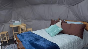 A tent with a bed, a small table, and a chair.