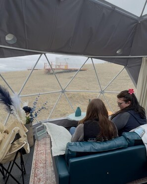 A tent with a geometric design, a sofa, a small table with a vase, and a decorative item with feathers.