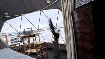 Una habitación con carpa, una cama, muebles de madera, un aparador y vista al agua.