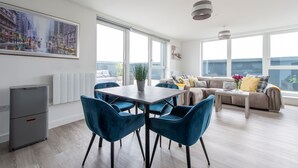 A modern living room with a dining area, large windows, and a view of the city. - Stylish Penthouse- Guests Favourite Just Amazing (London)