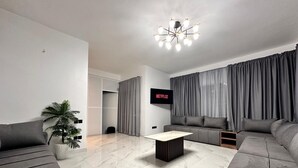 A modern living room with a flat-screen TV, grey sofas, a coffee table, and a potted plant. - Maison Ciel (Tanger)