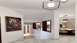 A hallway with a marble floor, a painting on the wall, and a dining area with a table and chairs. - Maison Ciel (Tanger)