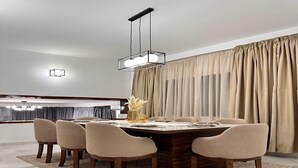 A dining area with a rectangular table, six chairs, a chandelier, and a large window with curtains. - Maison Ciel (Tanger)