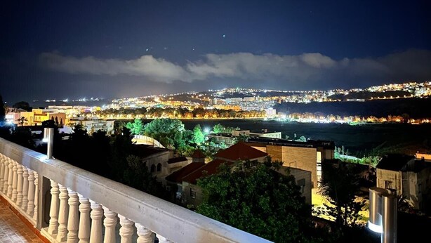 A nighttime cityscape with a view of a river and distant city lights. - Maison Ciel (Tanger)