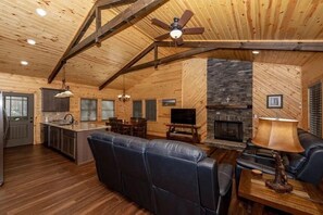 Ein Blockhaus-Interieur mit Küche, Essbereich und Wohnzimmer mit Kamin.