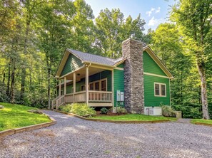 A green house with a stone chimney, a covered porch, and a gravel driveway. - Secluded 3bdrm/2bth cabin with hiking trail & bonfire pit, Peaceful Path (Townsend)