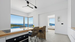 Eine moderne Küche mit einer großen Kochinsel, zwei Barhocker und Blick aufs Meer.