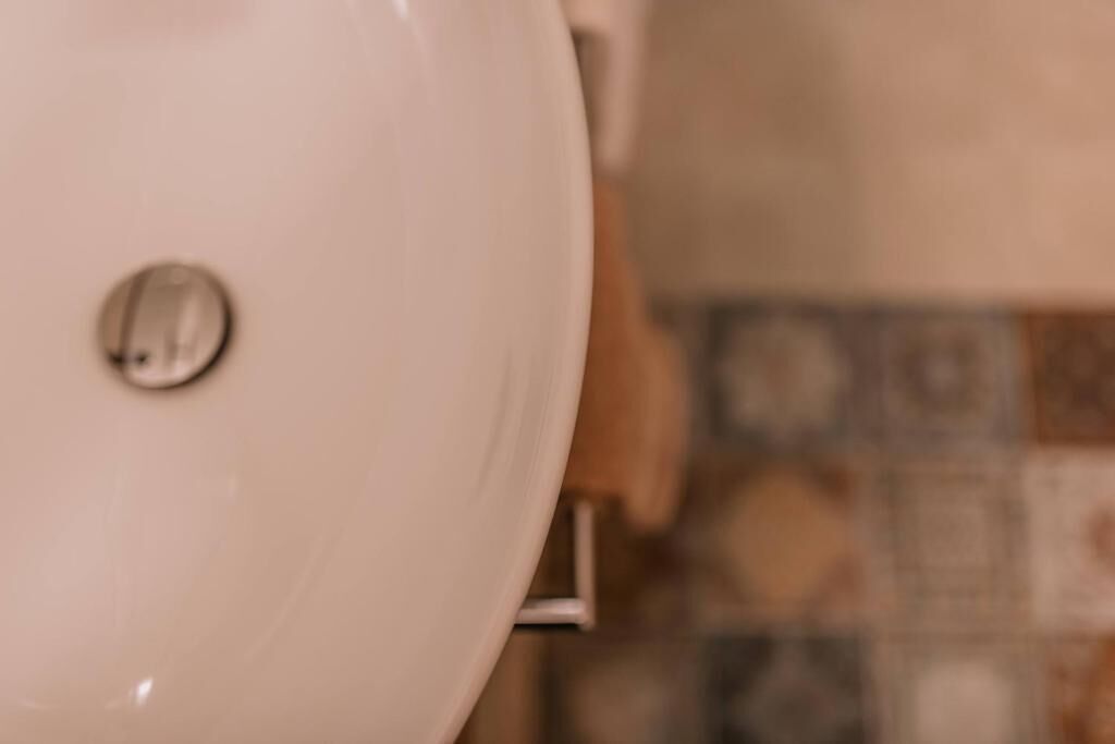 Une salle de bain avec un lavabo blanc, un miroir et un sol carrelé.