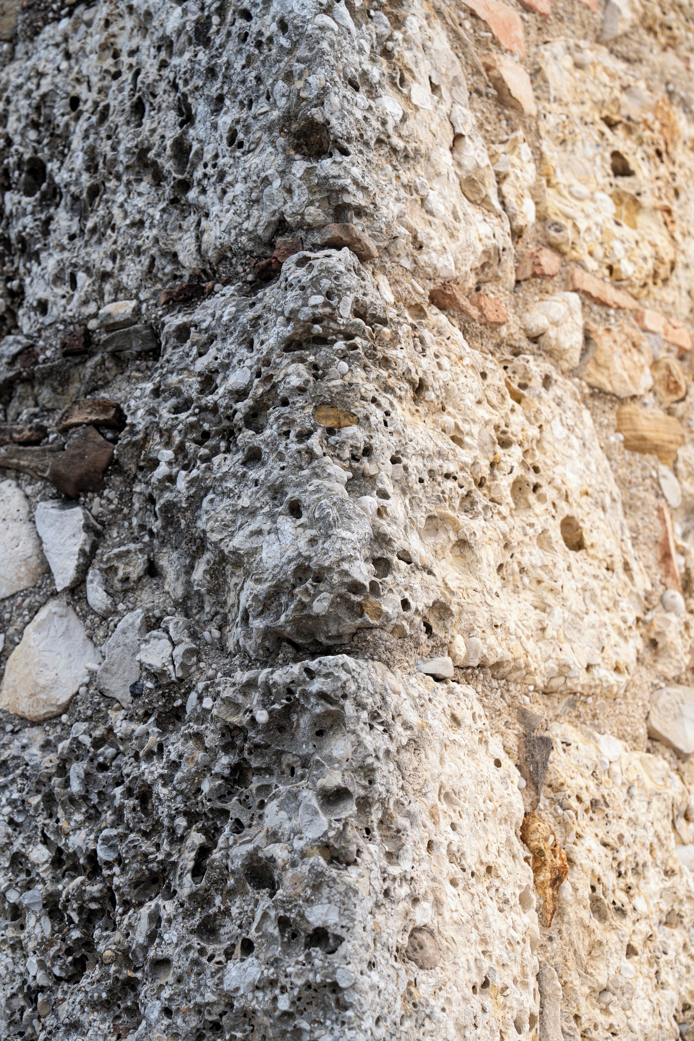 Un primo piano di un muro di pietra con diverse aperture e rientranze.