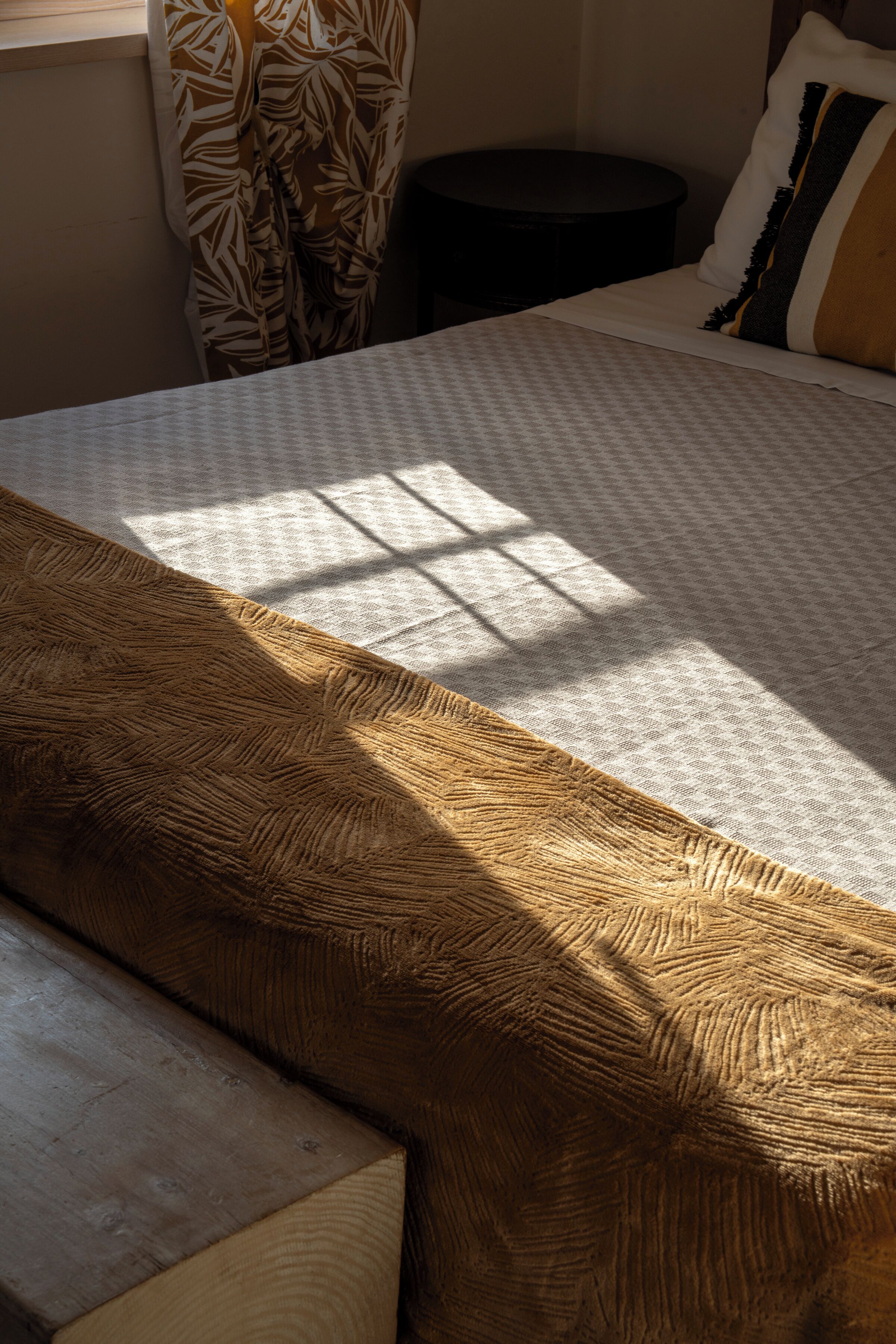 A bed with a patterned bedspread and a wooden headboard.