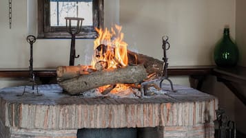 Ein Kamin aus Ziegelsteinen mit Feuer, darüber ein Fenster und ein Vorhang.