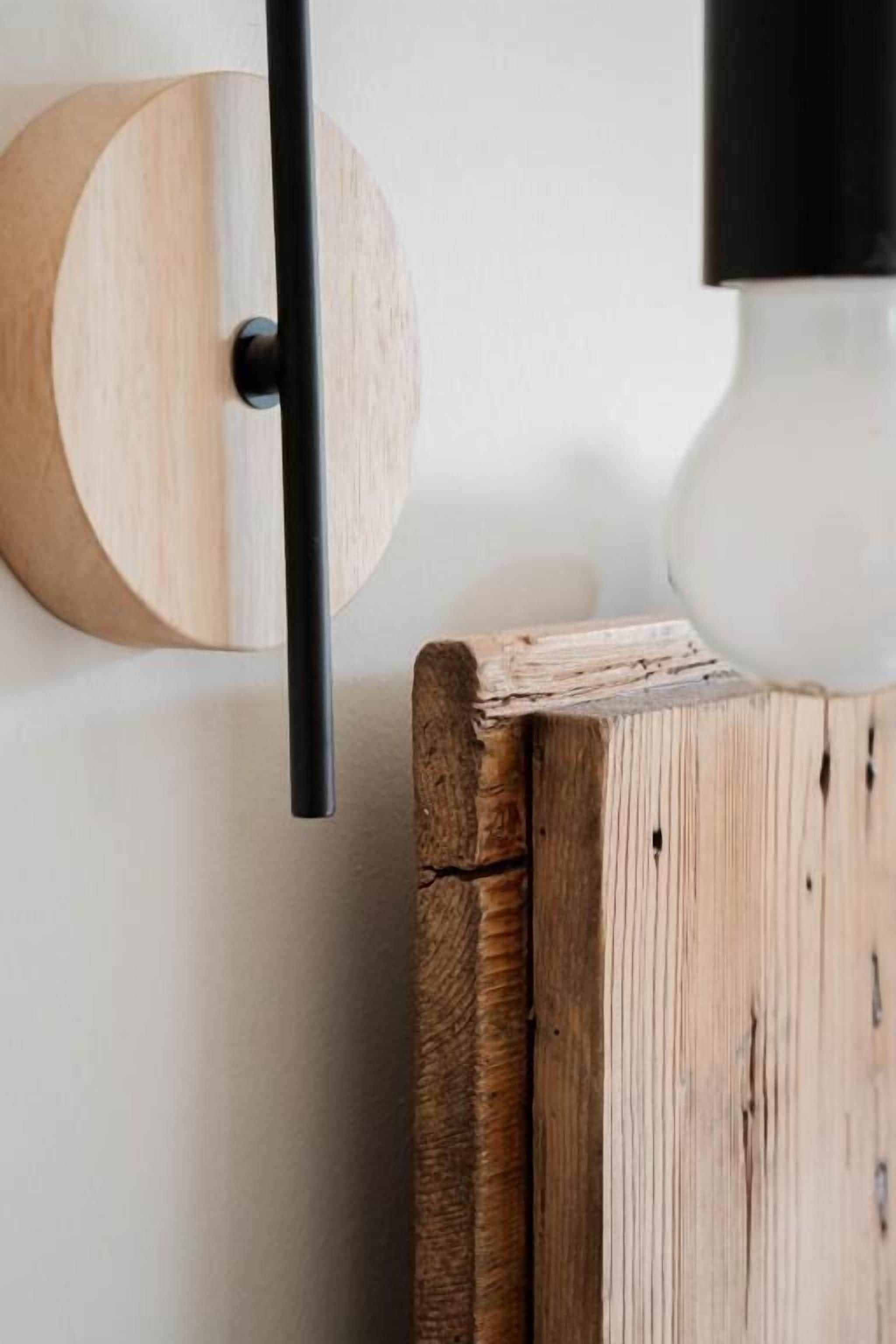 Un objeto de madera montado en la pared, con una varilla negra, una esfera blanca y una pieza de madera circular.