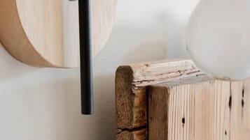 Un objeto de madera montado en la pared, con una varilla negra, una esfera blanca y una pieza de madera circular.