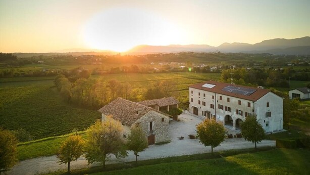 Paisaje rural con una edificación que presenta un patio, rodeado de campos y árboles.