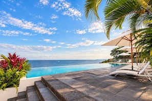 An infinity pool with a clear view of the ocean, surrounded by palm trees and lounge chairs. - Unique Designer Gem: Private Pool, Elevator, Views (Puerto Vallarta)