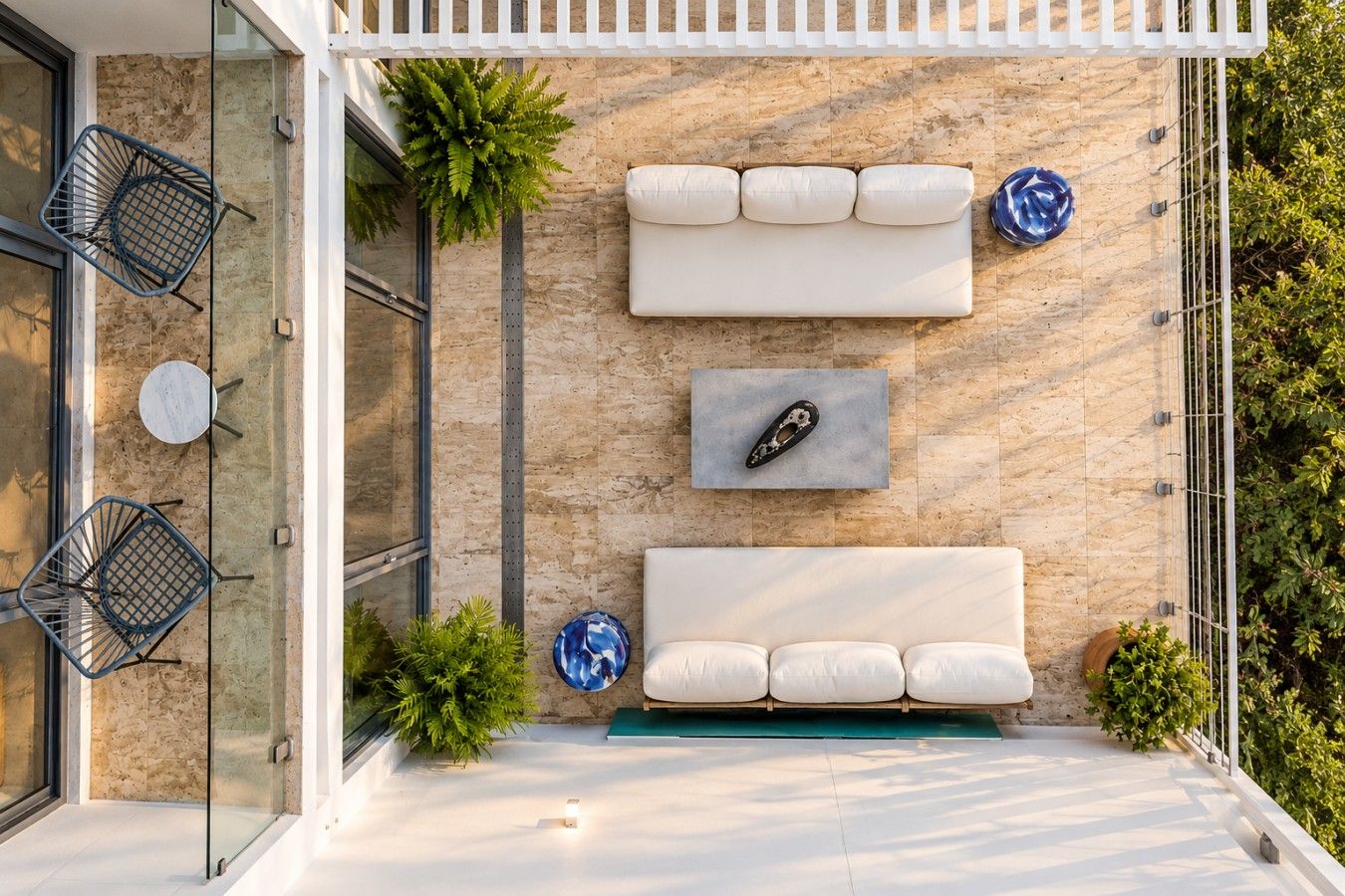 Un área de estar exterior moderna con un sofá blanco, dos platos decorativos azules y un estante de pared con un solo plato.