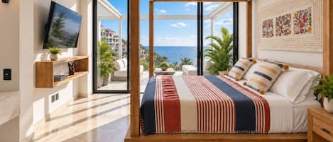 Un dormitorio moderno con una cama grande, un televisor y vista al mar.