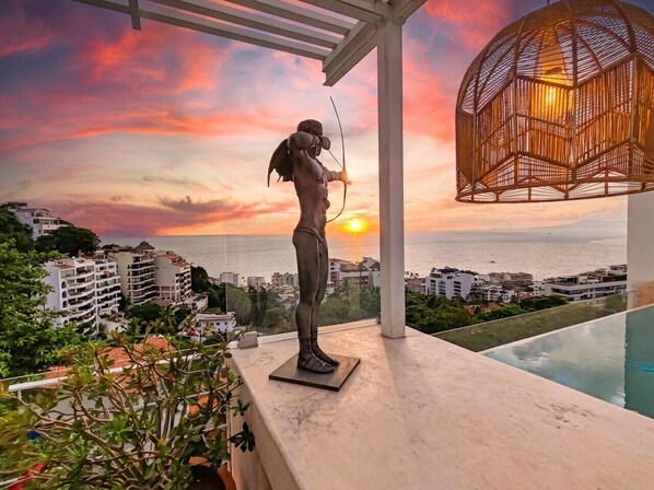 A statue of an archer on a balcony overlooking a cityscape and the ocean at sunset. - Unique Designer Gem: Private Pool, Elevator, Views (Puerto Vallarta)