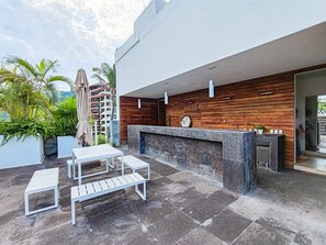Eine Terrasse im Freien mit einer Holzwand, einer Steinsitzbank und einem Tisch.