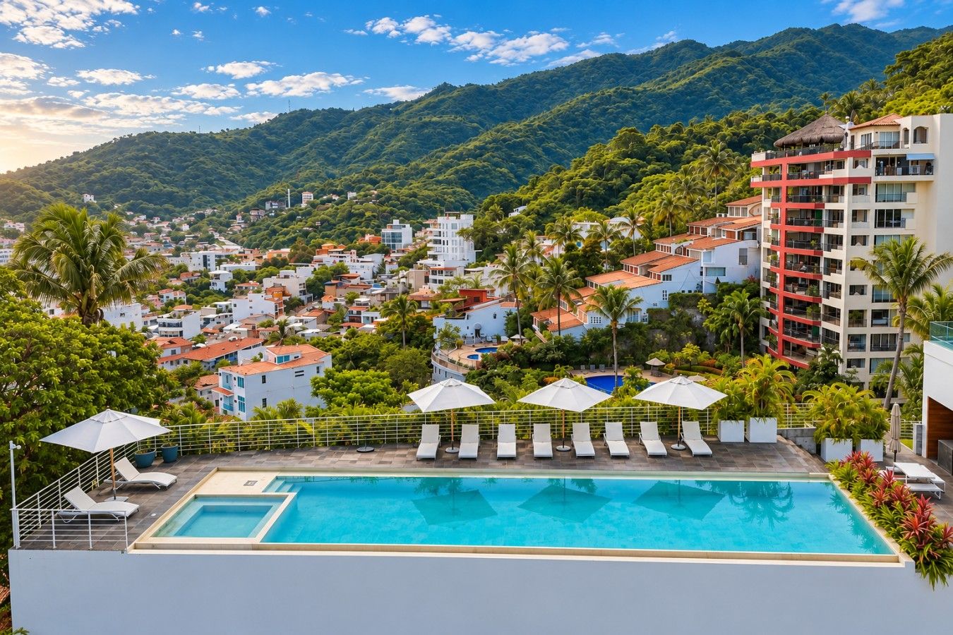 Ein Poolbereich mit Liegestühlen und Sonnenschirmen, umgeben von Gebäuden und einer Bergkulisse.
