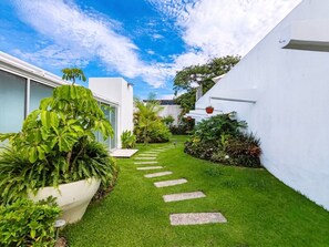 Ein gepflegter Garten mit einem Kiesweg, der zu einem weißen Gebäude führt.